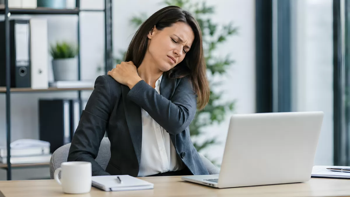 Bürofrau mit Nackenschmerzen vor dem Laptop