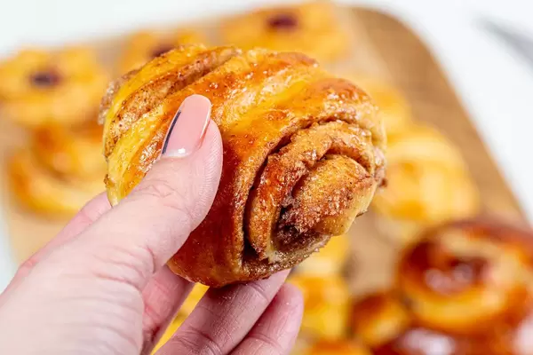 Bun roll with cinnamon in a woman's hand