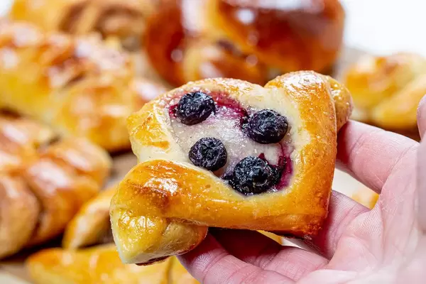 Bun with sugar and blueberries in hand closeup (Flip 2019)