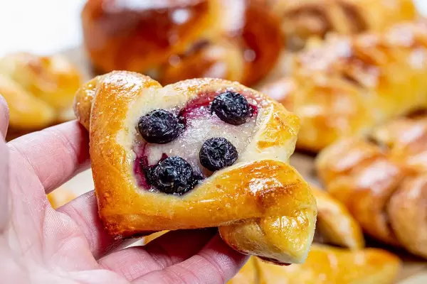 Bun with sugar and blueberries in hand closeup