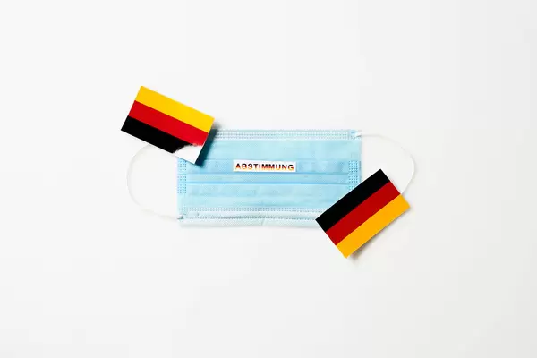 Bundestagswahl 2021: medizinische Gesichtsmaske mit Schrift "Abstimmung" und deutsche Flaggen