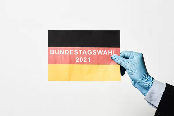 Bundestagswahl 2021: Schrift auf der deutschen Flagge mit Einmalhandschuh gehalten