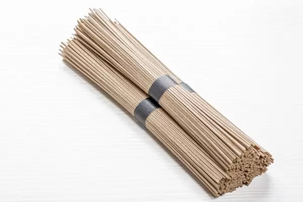 Bundles of raw buckwheat soba noodles on white wooden background