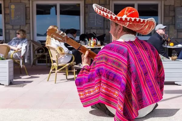 Bunt gekleideter Mann mit Sombrero und Poncho spielt Gitarre