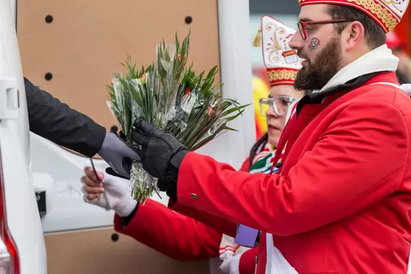 Bunt gekleideter Mann nimmt Blumen entgegen - Kölner Karneval 2018