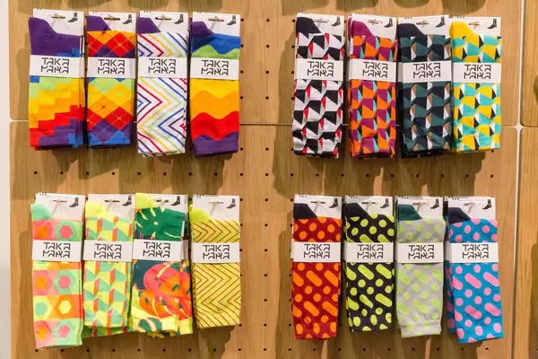 Bunt gemusterte Socken von Takapara führen zu garantierter Aufmerksamkeit an Holzwand