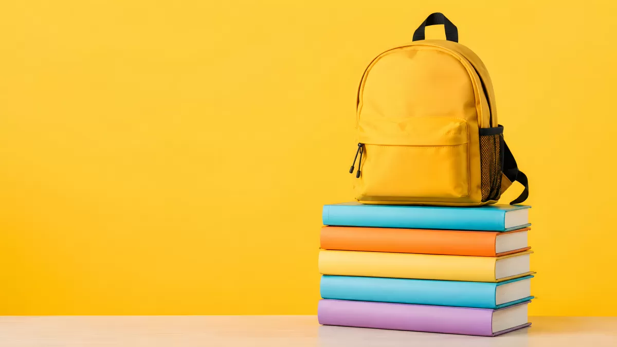Bunte Bücherstapel mit gelbem Schulrucksack