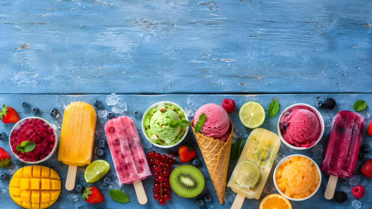 Bunte Eissorten und Früchte auf blauem Holz
