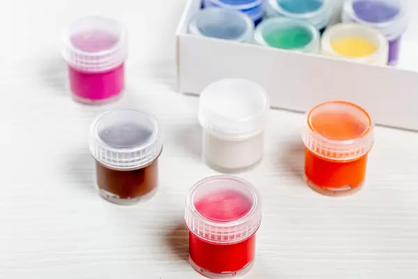 Bunte Farben in kleinen Schachteln auf braunem Holztisch