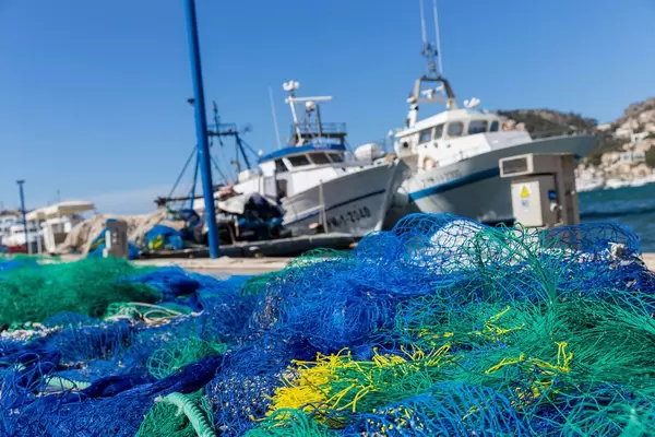 Bunte Fischernetze und Boote im Hintergrund