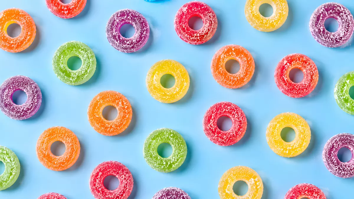 Bunte Fruchtgummi-Ringe mit Zucker auf blauem Hintergrund