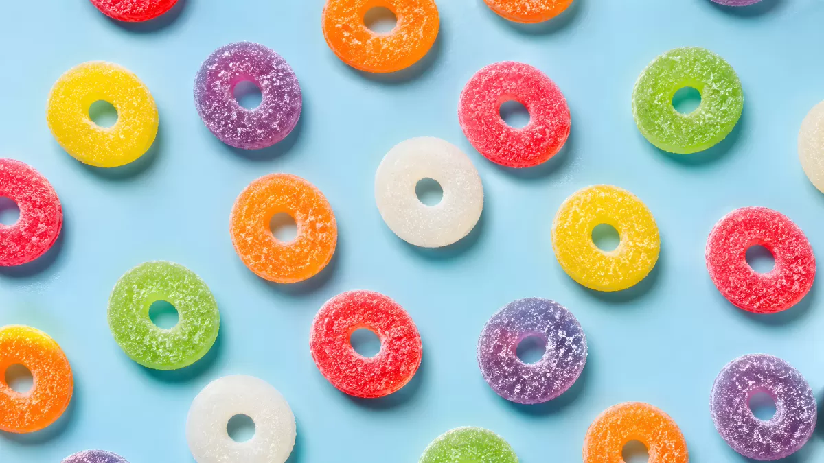 Bunte Fruchtgummiringe mit Zucker auf hellblauem Grund