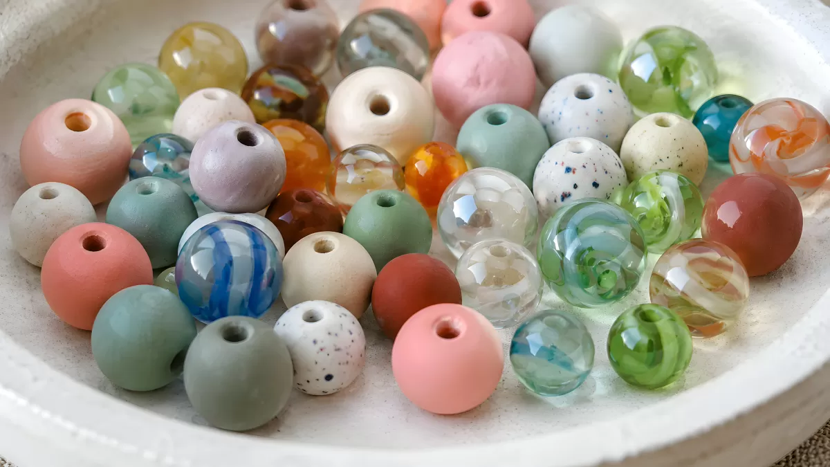 Bunte Glasperlen und Keramikperlen in weißer Schale