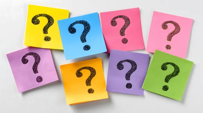Bunte Haftnotizen mit Fragezeichen auf weißem Hintergrund