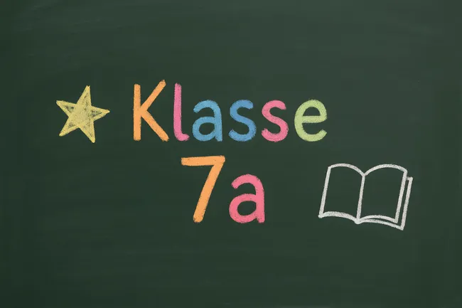 Bunte Kreideaufschrift 'Klasse 7a' auf Tafel