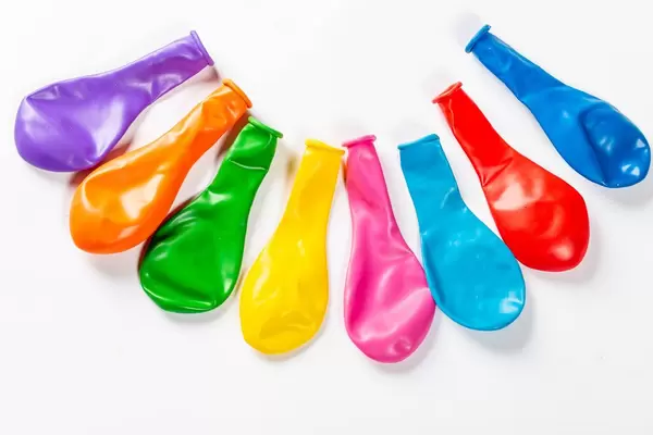 Bunte, leere Ballons in einem Halbkreis aufgereiht auf weißem Hintergrund