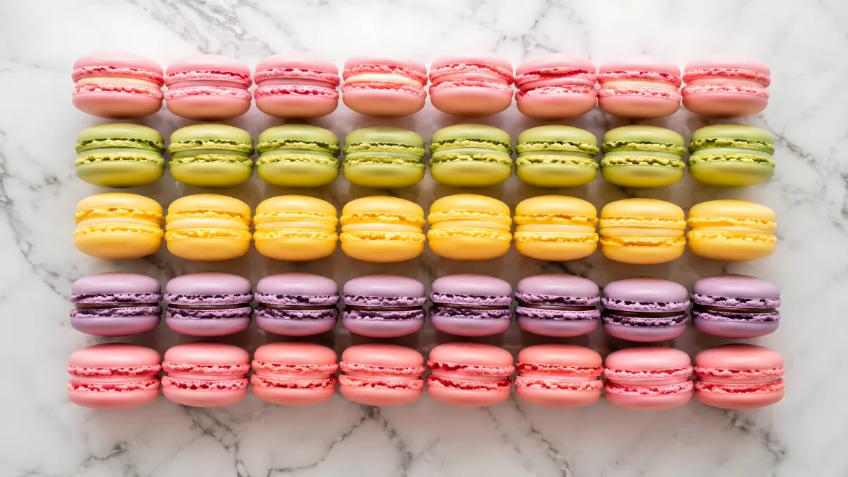 Bunte Macarons in Reihen auf weißem Marmor