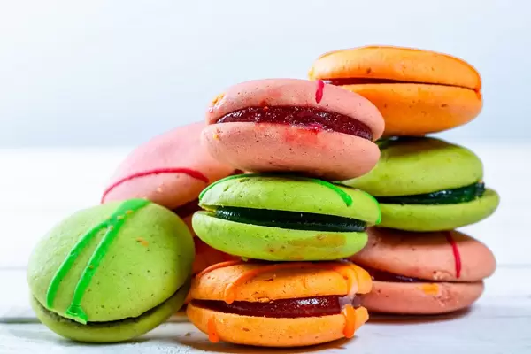 Bunte Macarons mit Füllung aufeinander gestapelt vor weißem Hintergrund