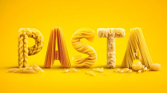 Bunte Nudeln in verschiedenen Formen und Größen auf gelbem Hintergrund