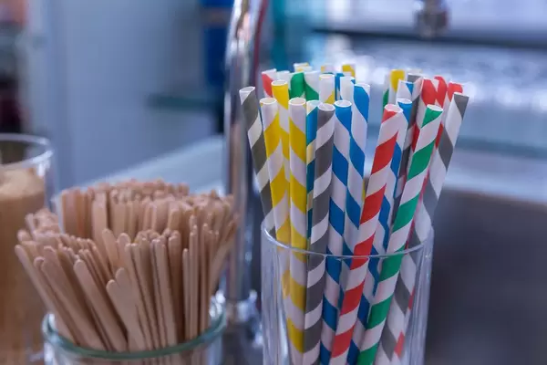 Bunte Papier-Trinkhalme und Holzstäbchen in Gläsern bei einem Buffet