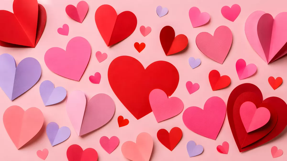 Bunte Papierherzen in Rot und Rosa auf hellem Hintergrund