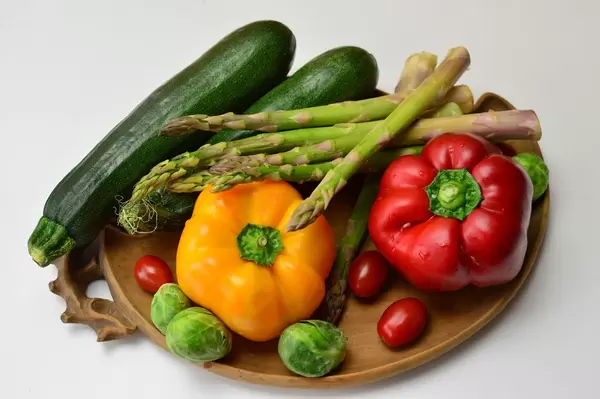 Bunte Paprika, Zucchini, grüner Spargel, Rosenkohl und Kirschtomaten auf Tonteller