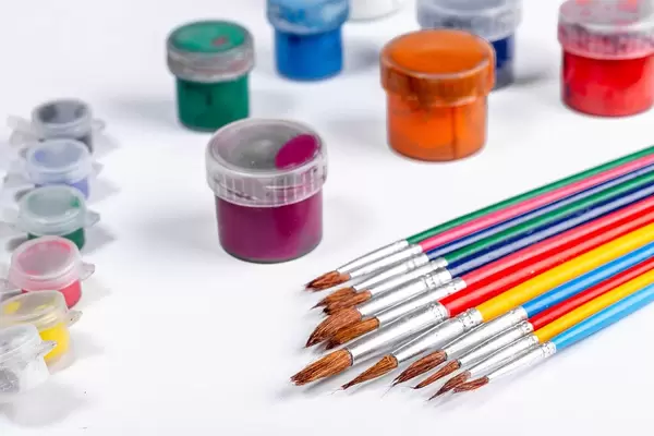 Bunte Pinsel und verschiedene Farbtöpfe als Zeichenset auf weißem Untergrund