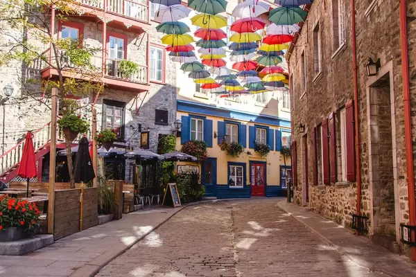Bunte Regenschirme über einer leeren Altstadtgasse an einem sonnigen Tag
