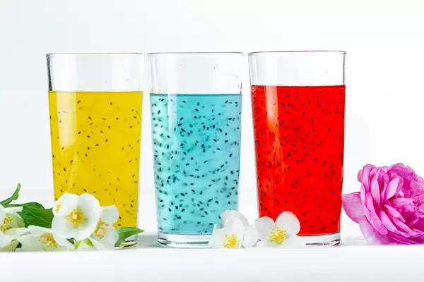 Bunte Sommercocktails in verschiedenen Farben, mit Blumen vor weißem Hintergrund