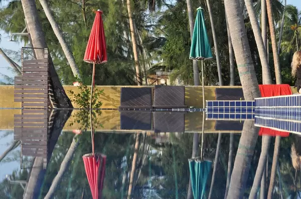 Bunte Sonnenschirme spiegeln sich im Wasser eines Schwimmbads