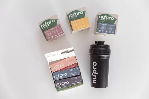 Bunte Verpackungen der Nu-Company, mit Rohkakao "NuCao", den Proteinshakes "NuPro" und einer schwarzen Trinkflasche für Sportler