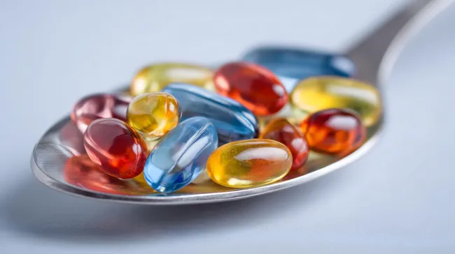 Bunte Vitaminpräparate auf Löffel