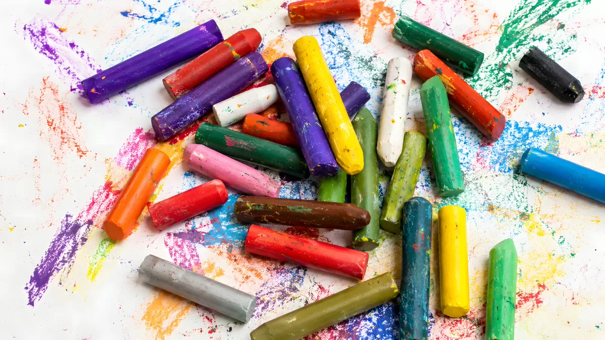 Bunte Wachsmalstifte verstreut auf weißem Papier