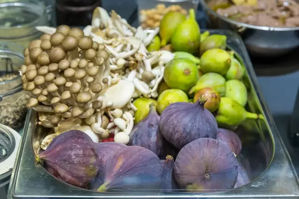 Bunte Zutaten für ein gesundes Mittagessen: Pilze, Feigen und Früchte in einer Aufbewahrungsbox