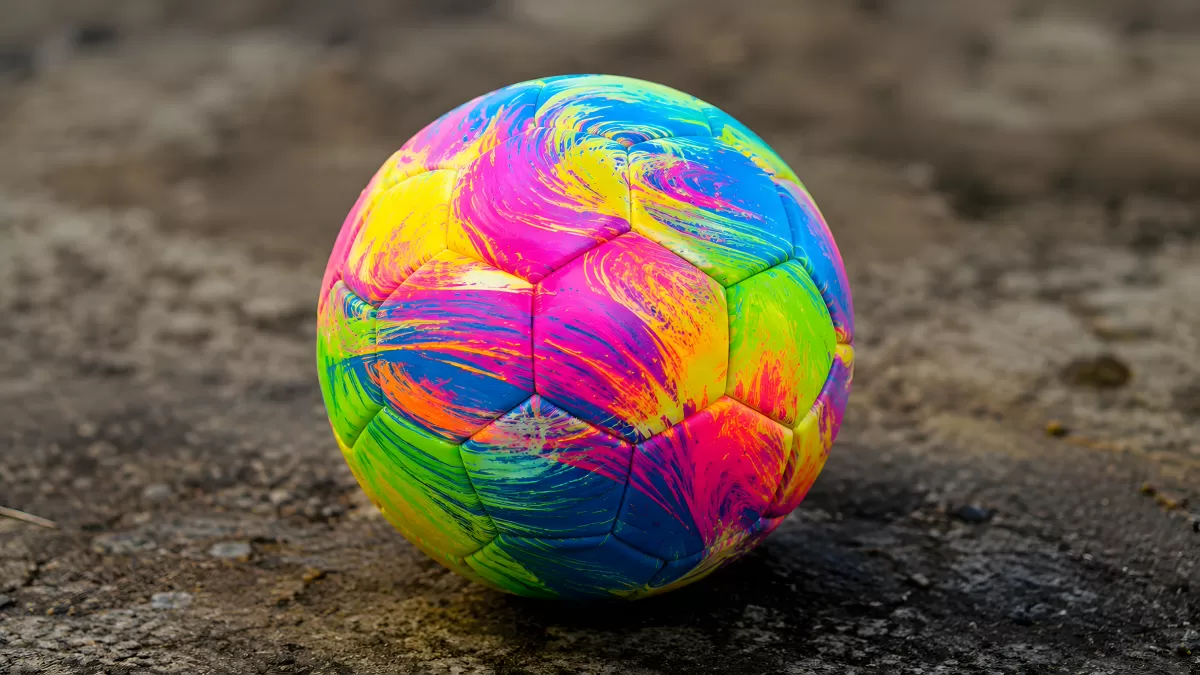 Bunter Fußball mit Farbwirbeln auf Asphalt