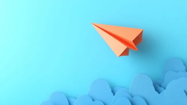 Bunter Papierflieger vor blauem Hintergrund