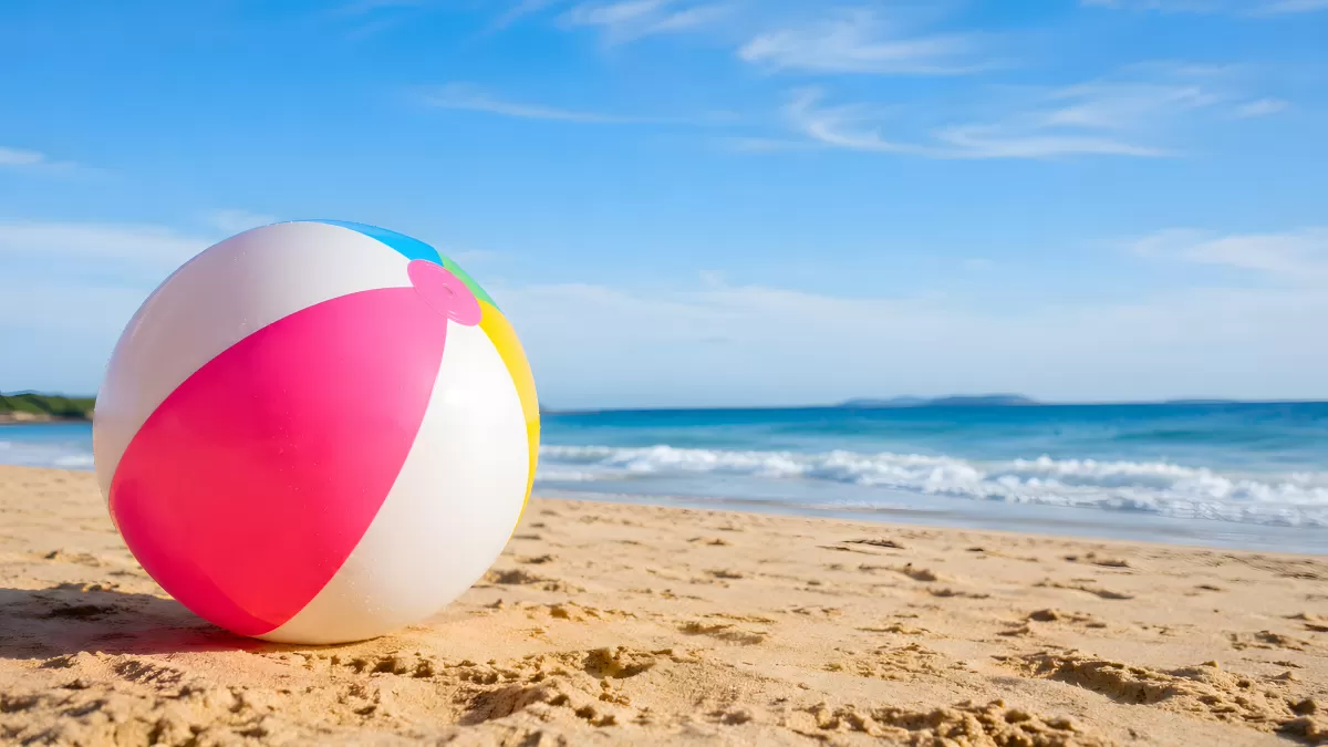 Bunter Wasserball am Sandstrand mit blauem Meer