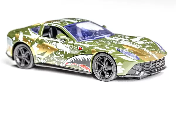 Buntes Metallauto als Kinderspielzeug vor weißem Hintergrund