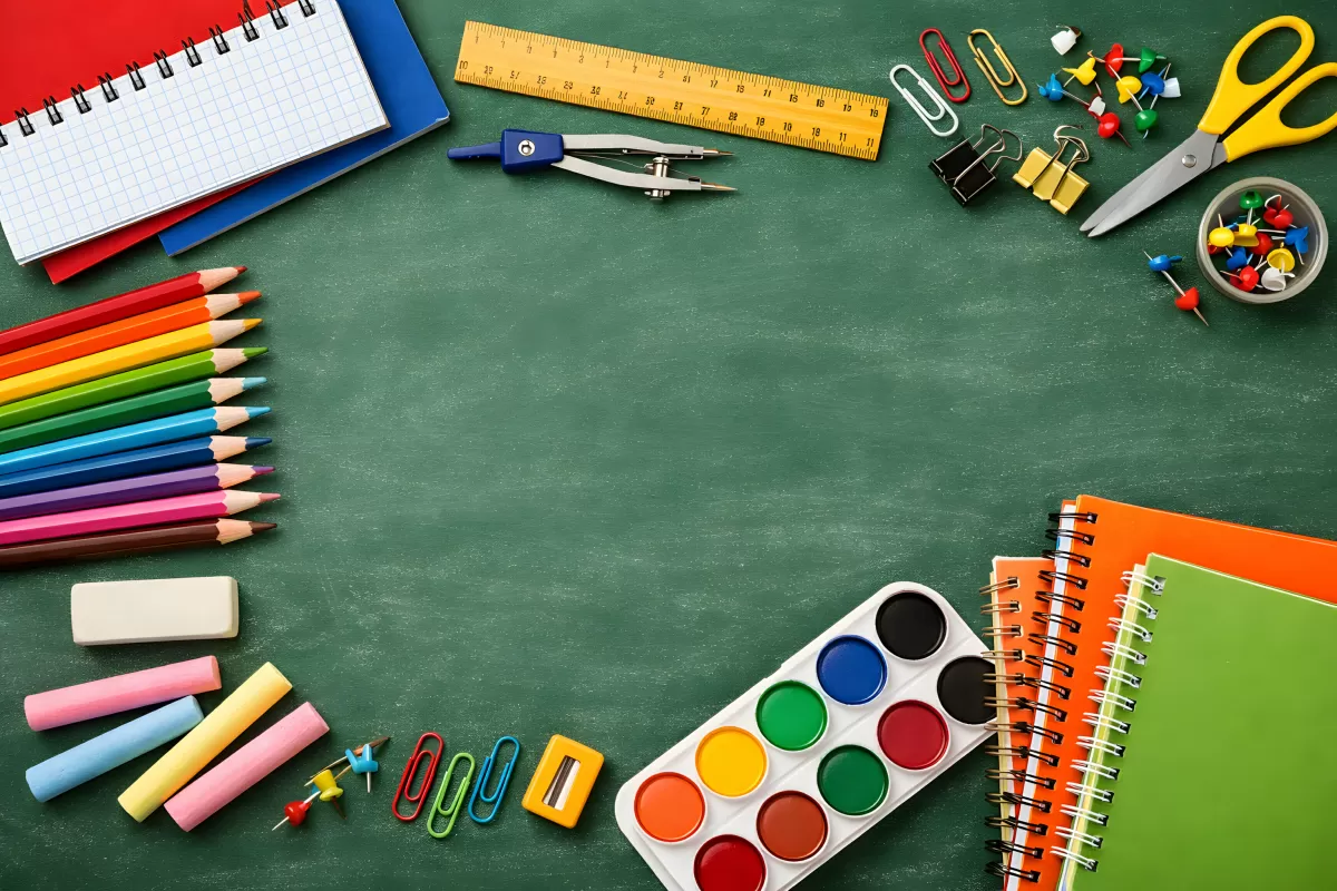 Buntes Schulzubehör auf grüner Kreidetafel