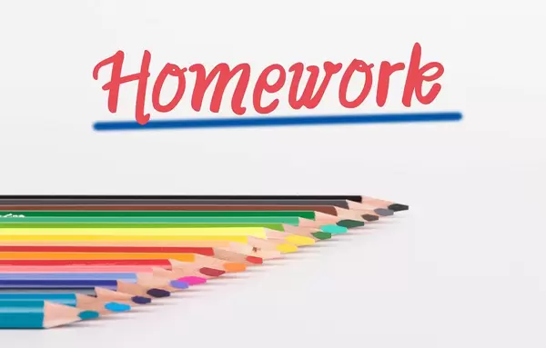 Buntstifte vor weißem Hintergrund mit rotem "Homework" Text