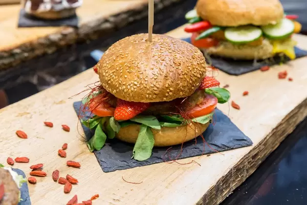 Burger mit Erdbeeren, Gemüse und Salat auf einem Steinteller