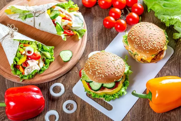 Burgers and pita bread with fresh vegetables on a brown wooden table (Flip 2019)