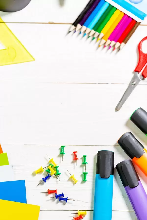 Büro- oder Bastelutensilien mit bunten Textmarkern, Buntstiften, farbigem Papier, Schere und Pinwand-Nadeln