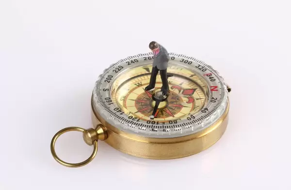 Businessman figure standing on compass