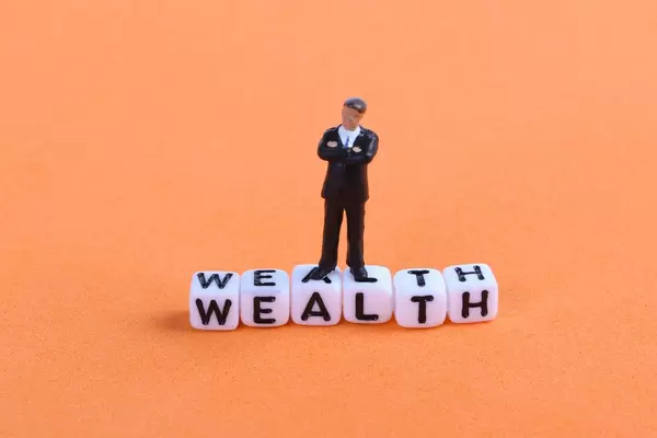 Businessman figure standing on Wealth text