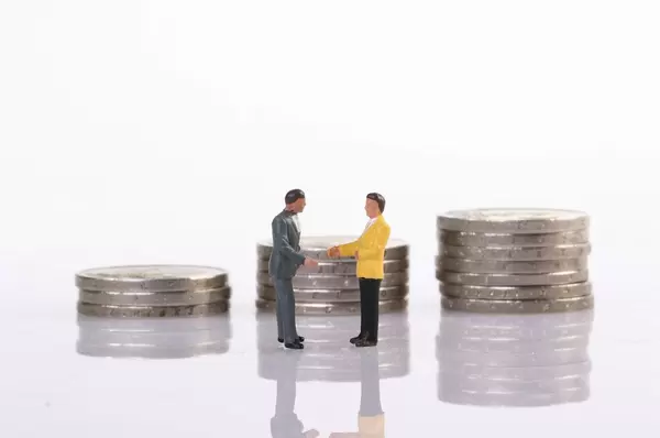 Businessman handshake in front of coin stacks