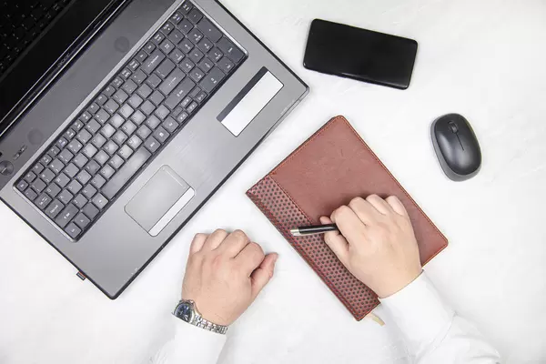 Businessman in front of computer with mobile phone and diary