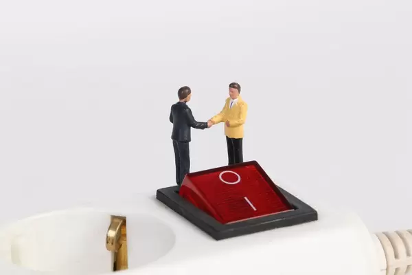 Businessman shaking hands on white electric splitter with red switch