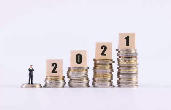 Businessman, stack of coins and wooden cubes with 2021 text