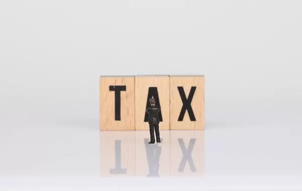 Businessman standing in front of Tax text